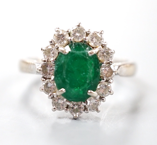 A modern 18ct white gold emerald and diamond set oval cluster ring, size O, gross weight 4.6 grams.